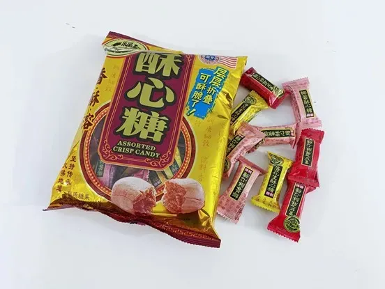 一袋金色包装的酥心糖,旁边散落着红色、粉色和黄色包装的独立糖果。