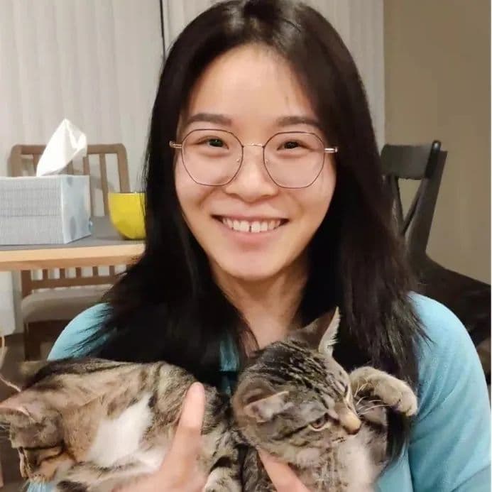 戴眼镜的年轻女子抱着两只虎斑猫微笑