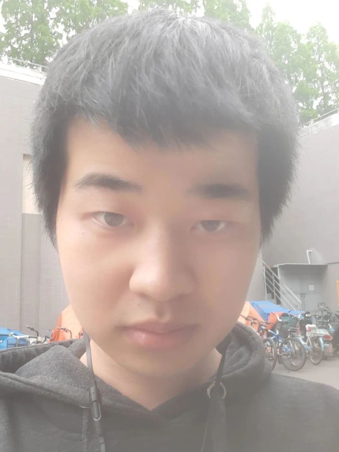 一名年轻男子自拍,留着深色头发,穿着深色连帽衫,戴着耳机。