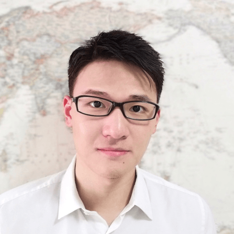 年轻亚洲男子戴眼镜穿白衬衫,背景是模糊地图。