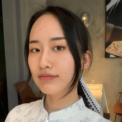 一位年轻的东亚女性,深色头发,穿着浅色图案上衣,直视镜头。